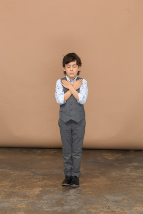 Vue de face d'un garçon mignon en costume gris debout avec les mains sur les épaules
