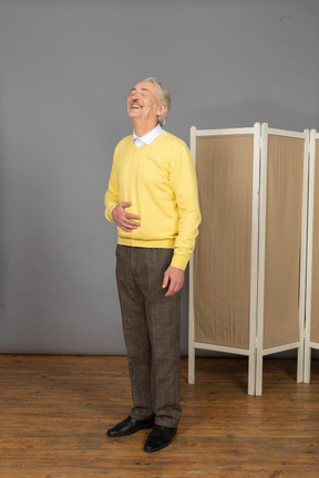Vue de trois quarts d'un vieil homme en riant mettant la main sur l'estomac