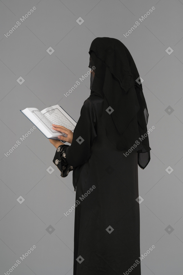 A covered woman standing with the quran back to camera