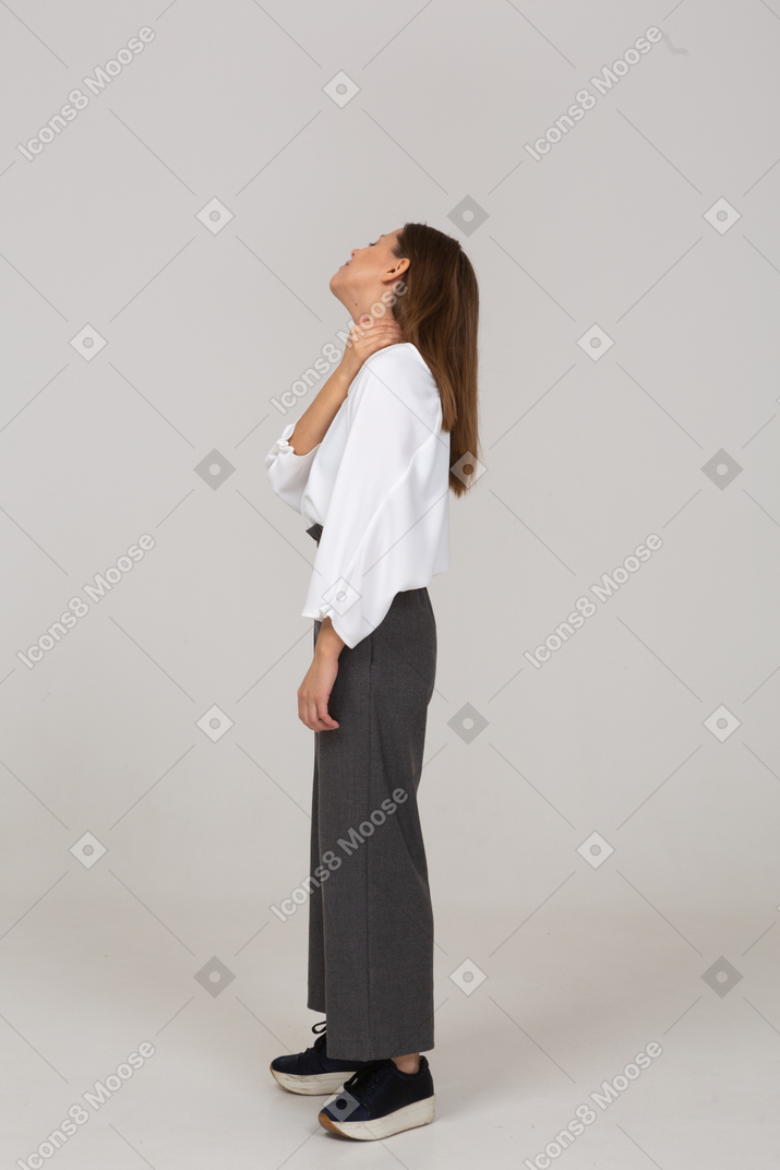 Side view of a young lady in office clothing touching neck