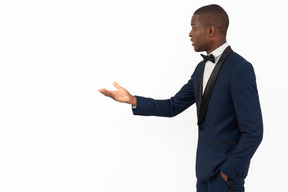 Good-looking young business man standing in profile and pointing with his hand