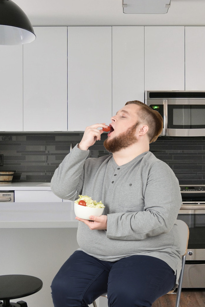 A man eating a salad in his kitchen