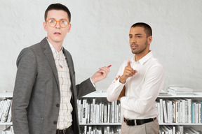 Two business men standing in front of a bookcase