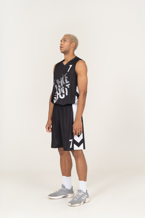 Three-quarter view of a bored young male basketball player looking up