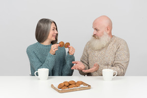 Mulher mais velha segurando cookies e seu marido não entendo