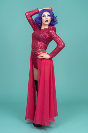 Portrait of a drag queen posing with hand on hip & raising an arm above head