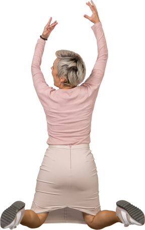 腕を上げてジャンプするカジュアルな服装の女性の背面図