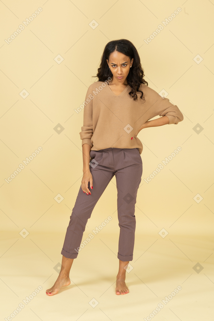 Front view of an offended young dark-skinned female putting hand on hip