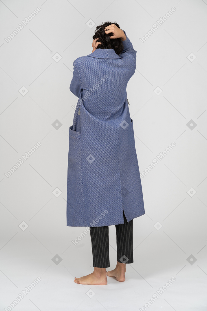 Back view of a woman in coat pulling her hair