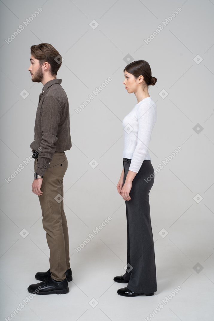 Vista lateral de um jovem casal surpreso com roupas de escritório, levantando as sobrancelhas