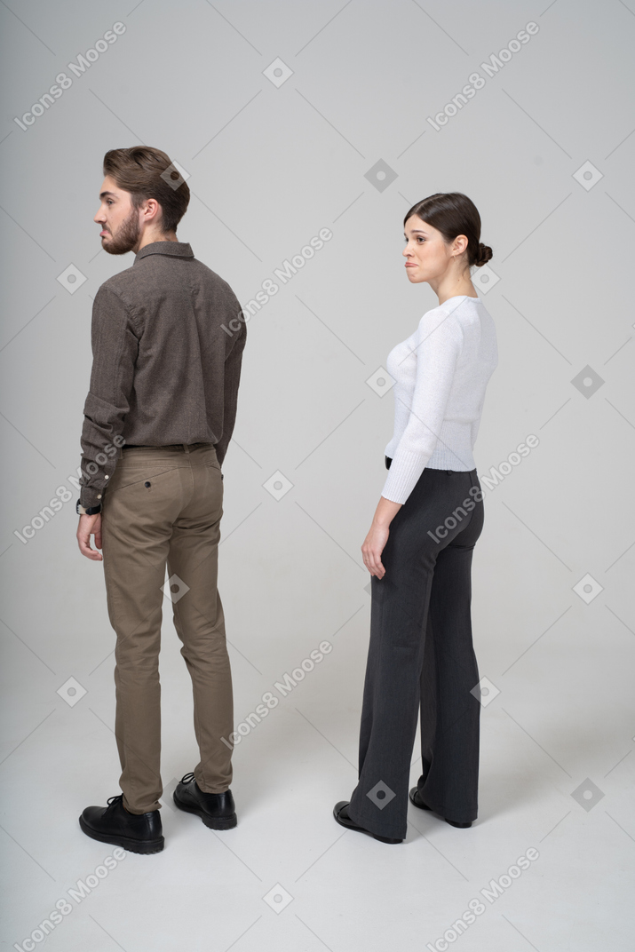 Three-quarter back view of a cute pouting couple in office clothing