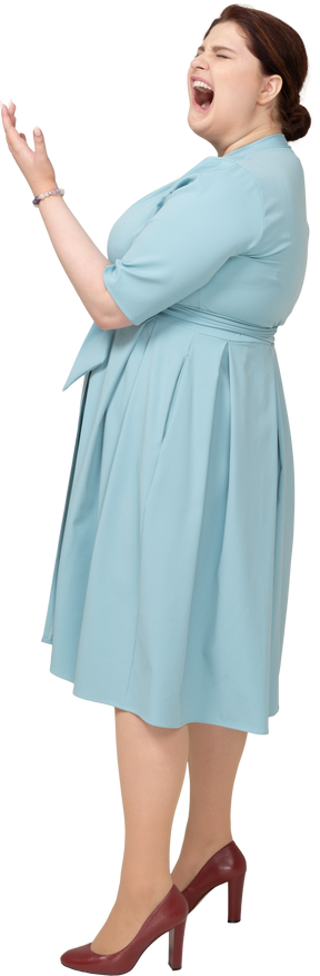 Vista laterale di una donna in abito blu che sbadiglia