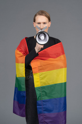 Person wrapped in rainbow flag holding megaphone