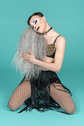 Smiling drag queen standing on knees and holding wig