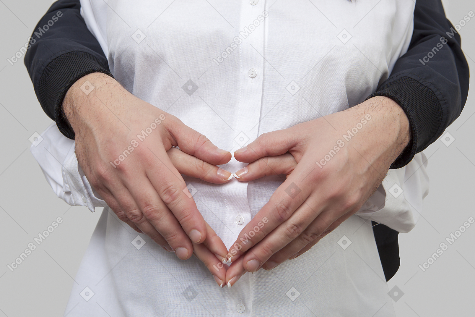 Close up of man's hands holding woman's hand from behind and forming heart