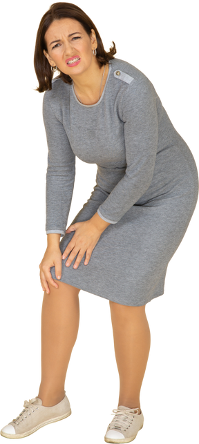 Side view of a woman in grey dress touching knee