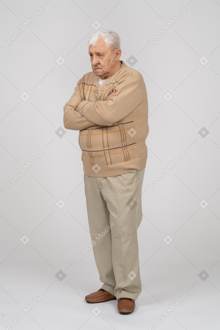Vista lateral de um velho em roupas casuais em pé com os braços cruzados