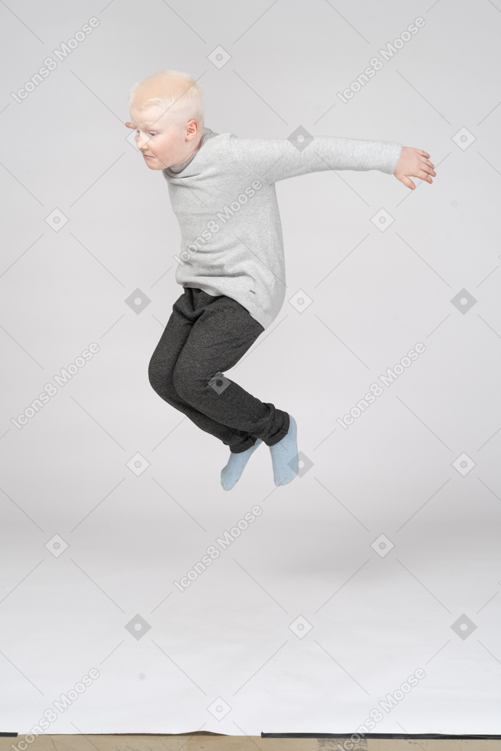 Visão de três quartos de um menino pulando alto