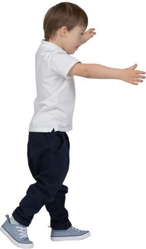 Vista lateral de um menino andando com as mãos estendidas