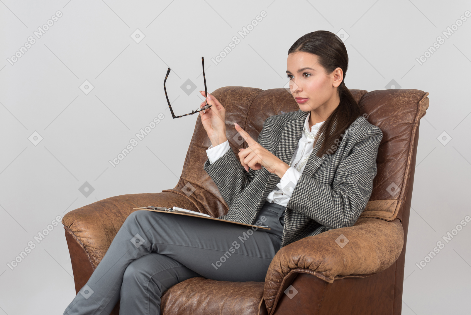 Serious young female psychologist sitting in chair and seems to be involved in work