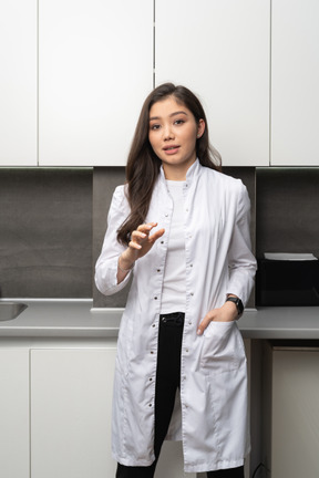 Vue de face d'une jeune femme médecin gesticulant et regardant la caméra