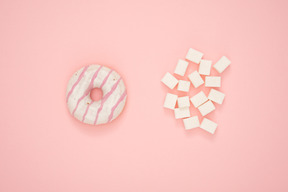 Cubetti di zucchero e ciambella su sfondo rosa
