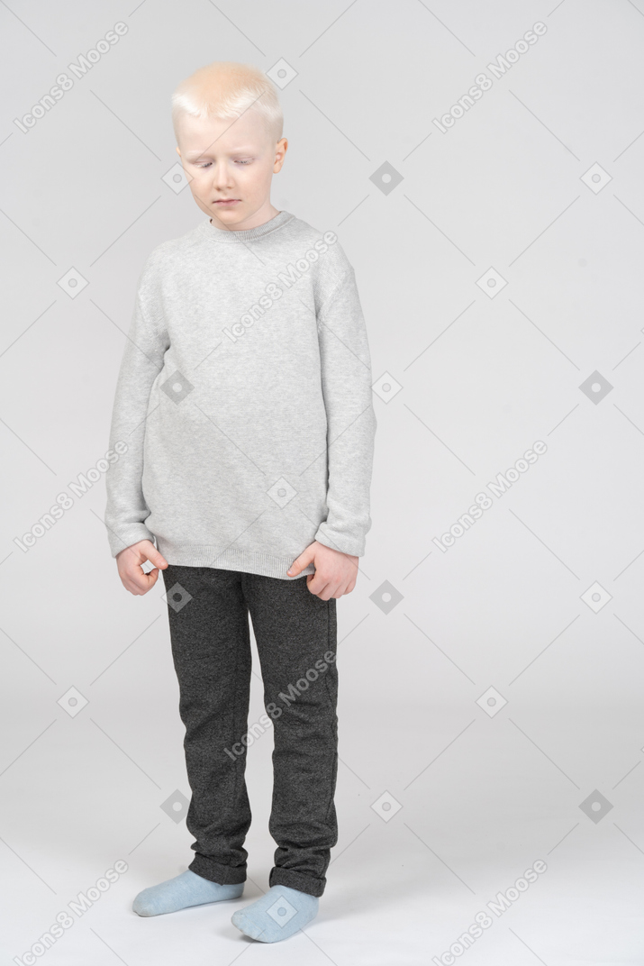 Front view of a kid blonde little  sad boy looking down