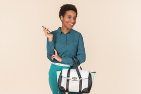 Smiling young woman holding bag and phone