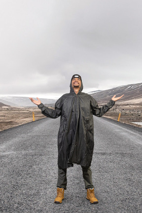 A man in a raincoat standing on a road