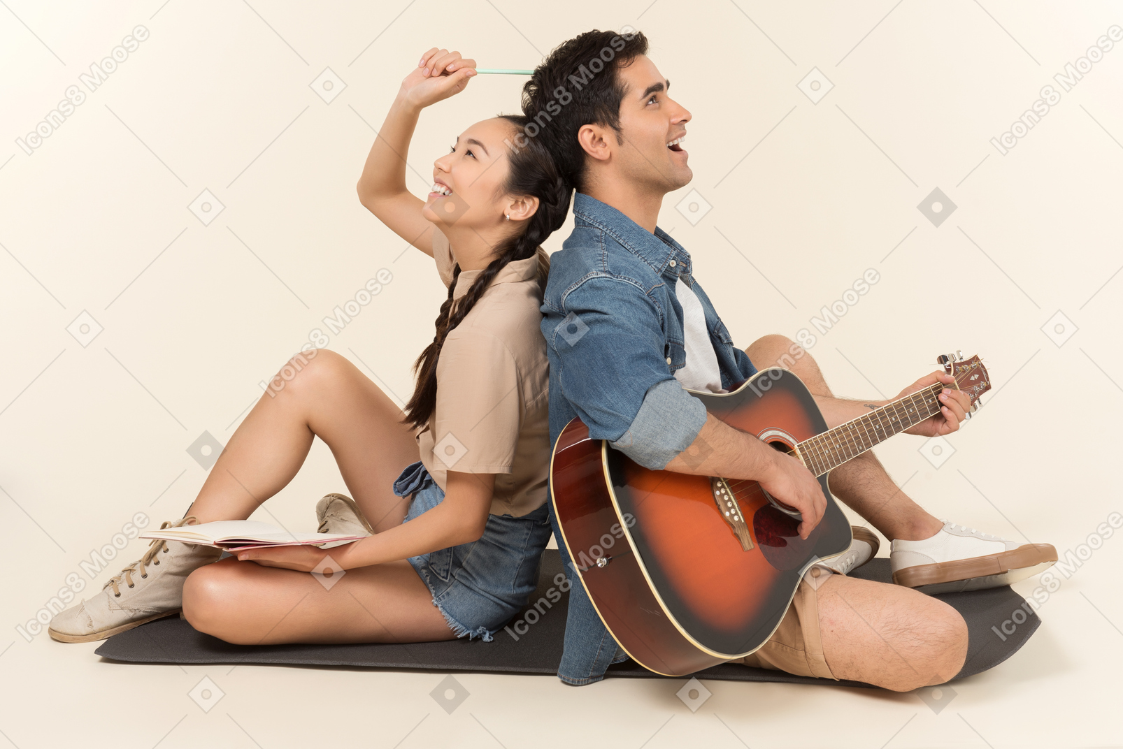 Riendo pareja interracial sentado espalda con espalda y hombre tocando la guitarra