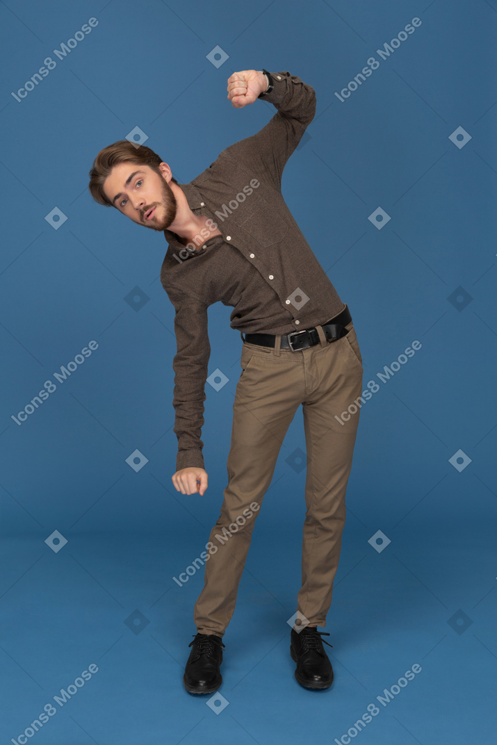 Танцующий стройный молодой человек смотрит в камеру