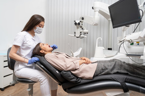 Full-length of a female dentist examining her patient in a hospital cabinet