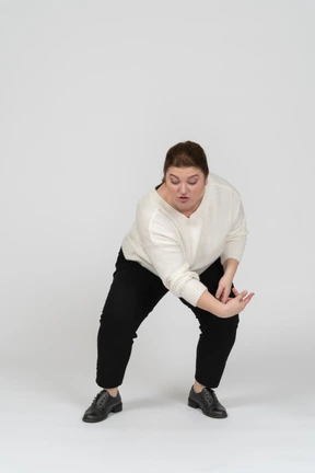 Front view of a plump woman in casual clothes squatting