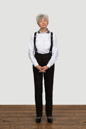 一位老不高兴女性在做鬼脸和手牵着手的办公室衣服的前视图