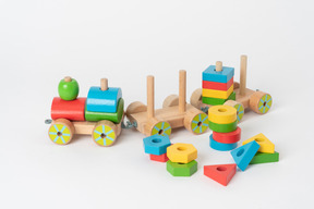 평범한 흰색 배경에 누워 다채로운 나무 장난감 기차와 다양한 색상의 기하학적 모양