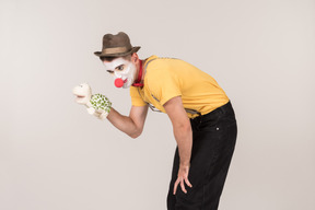 Bend male clown holding toy turtle