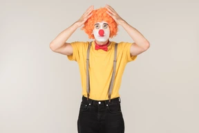 Troubled looking male clown touching wig he's wearing