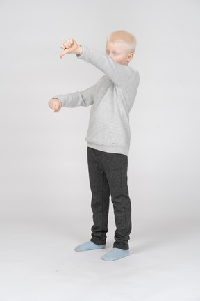 Little boy showing a fist and thumb down