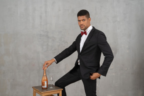 Homem de pé com a mão em cima de uma garrafa de champanhe