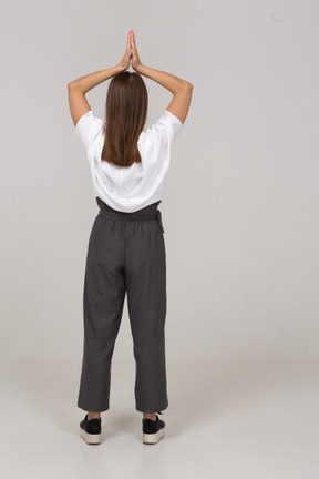 Vista posteriore di una giovane donna in abiti da ufficio che si tiene per mano sopra la testa