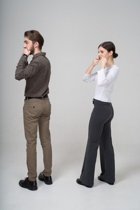 Three-quarter back view of a young couple in office clothing stretching mouth
