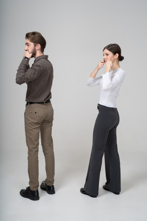 Vue arrière des trois quarts d'un jeune couple en vêtements de bureau qui s'étend de la bouche