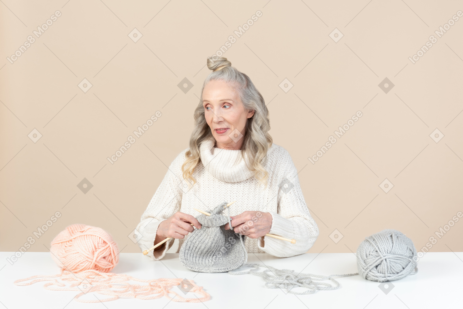 Aged woman focused on knitting and looking aside