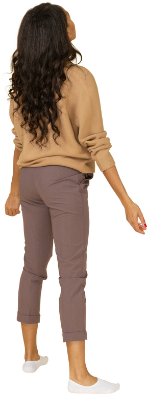 Vista posteriore di tre quarti di una giovane donna dalla pelle scura in piedi con le braccia aperte