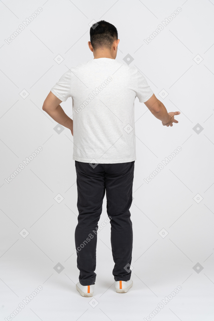 Back view of a man in casual clothes pointing at something with a hand