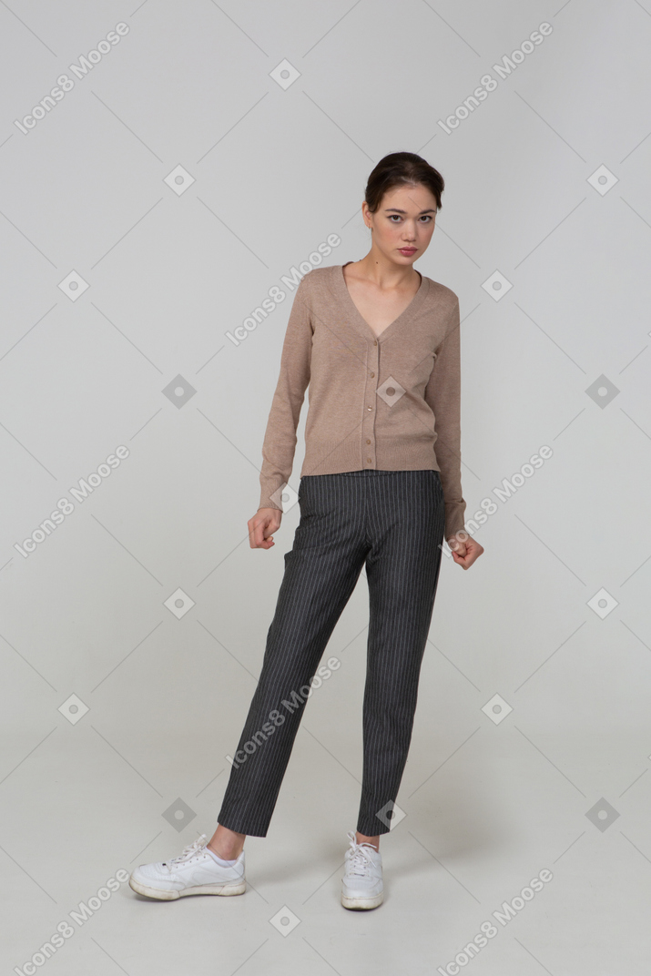 Front view of an angry young lady in pullover and pants clenching her fists