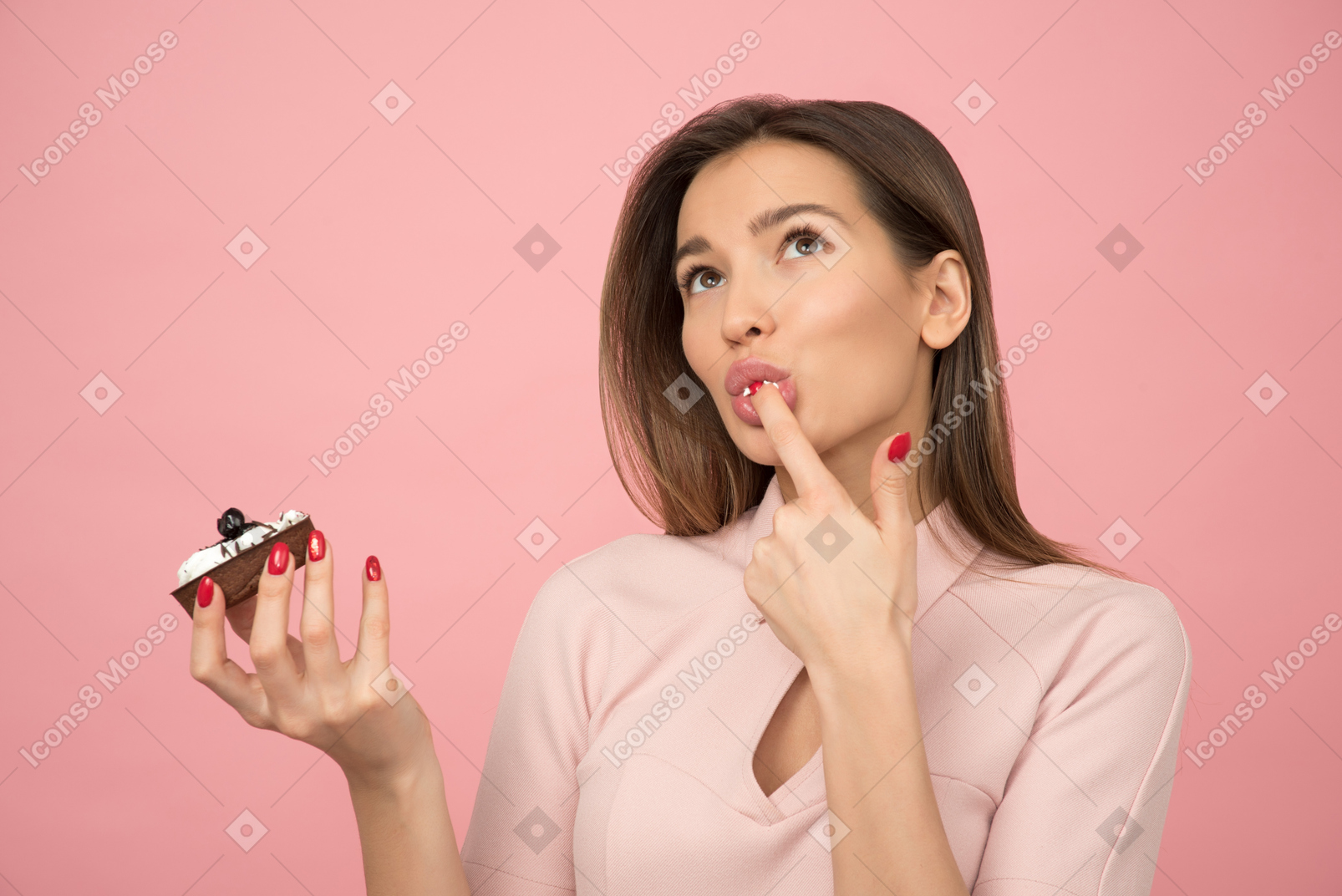 Attractive girl eating a cake and licking her finger