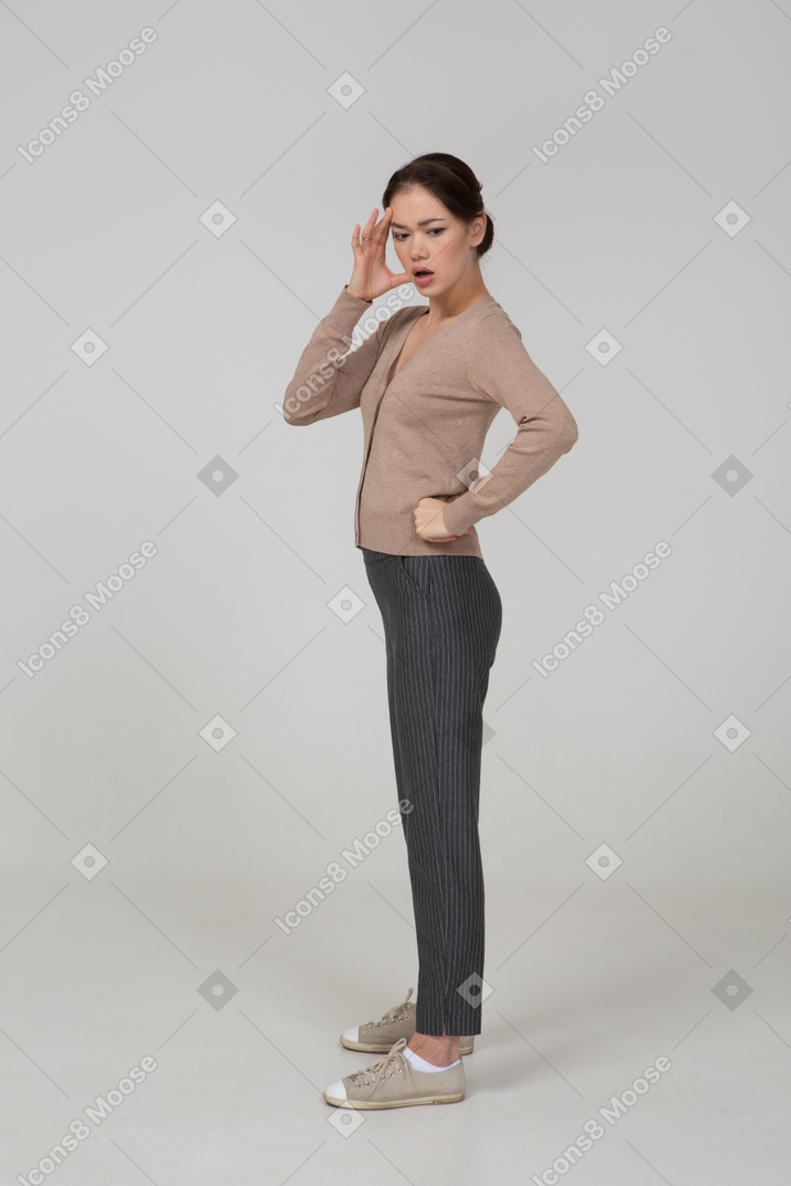 Vista laterale di una giovane donna in pullover e pantaloni che toccano la sua testa