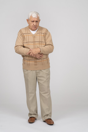 Front view of a grumpy old man in casual clothes looking at camera