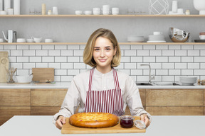 A woman in an apron holding a cake on a cutting board